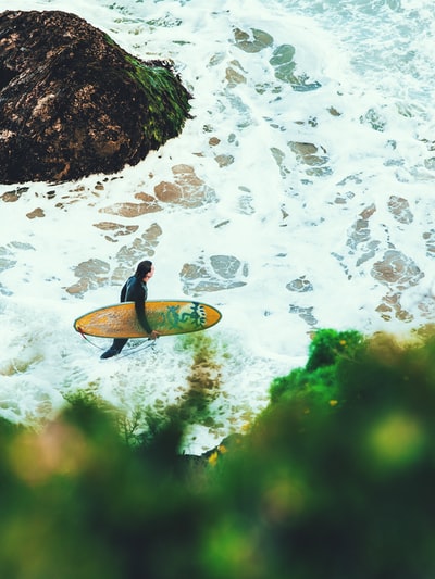 The man carrying a surfboard on the beach
